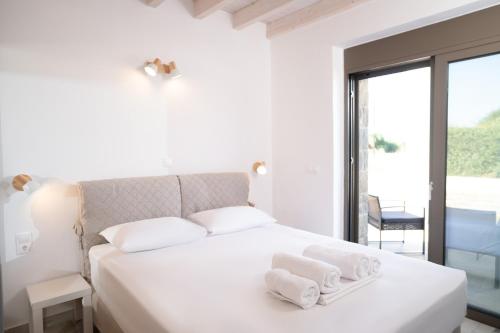 a bedroom with a white bed with towels on it at PETRINO FOINIKOUNTA in Finikounta