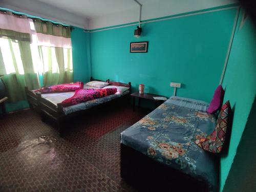 een slaapkamer met 2 bedden en blauwe muren bij Hotel Gaurav in Darjeeling