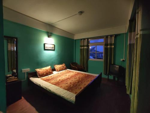 een slaapkamer met een bed met een groene muur bij Hotel Gaurav in Darjeeling