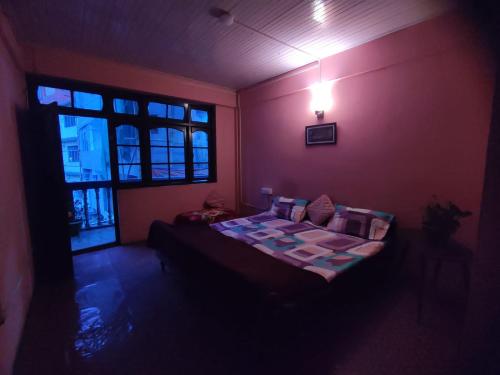 een slaapkamer met een bed in een kamer met een raam bij Hotel Gaurav in Darjeeling