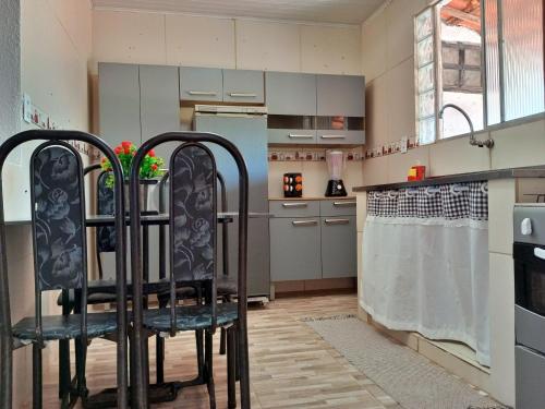 a kitchen with two black chairs in a room at Conforto 100 mts da praia in Barra de São Miguel