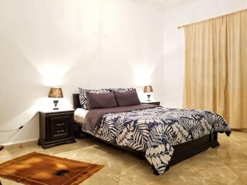 ein Schlafzimmer mit einem Bett, einem Tisch und zwei Lampen in der Unterkunft Appartement 200 m 2 + 5 min du c.c.o in Oran