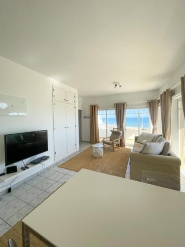 a living room with a television and a couch at LINHA D ÁGUA - ap in Salema