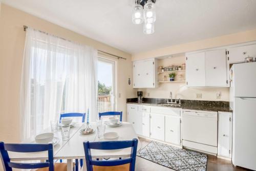 a kitchen with a white table and blue chairs at Shore Delight Waldport Home and Deck, Walk to Beach in Waldport