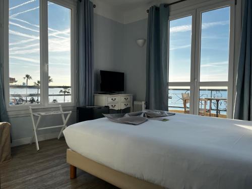 a bedroom with a large bed with a view of the ocean at H&ocirc;tel du Bord de Mer "Le Vanill&eacute;" in Cagnes-sur-Mer