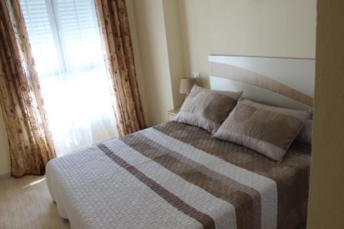 a bedroom with a large bed with a window at Apartamento Mariposa in Torrevieja