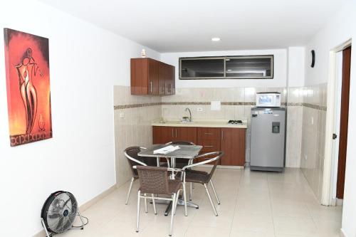 a kitchen with a table and chairs and a refrigerator at Apartahotel Los Cerezos in Neiva