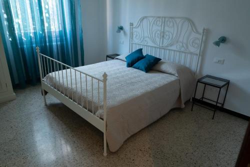 uma cama branca com almofadas azuis num quarto em La casa di Nettuno em La Spezia