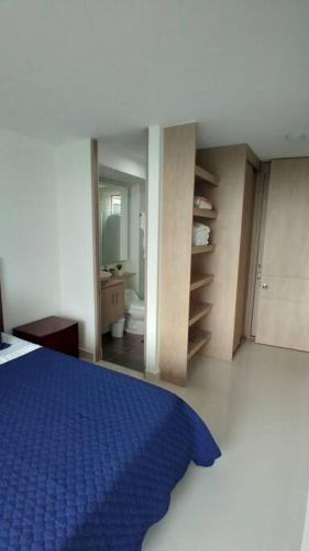a bedroom with a blue bed and a bathroom at Hermoso Apartamento Ricaurte Peñazul La Morada. in Ricaurte