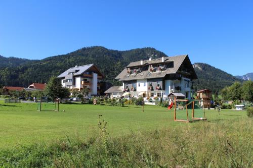 una casa grande con un parque infantil en un campo en Seehaus Winkler en Weissensee