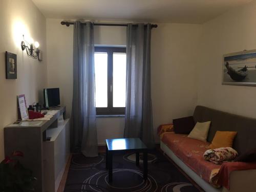een woonkamer met een bank en een raam bij La casina nel Borgo in Cetona