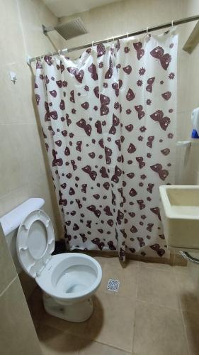 y baño con aseo y cortina de ducha de mono. en Habitacion con baño privado en Salta