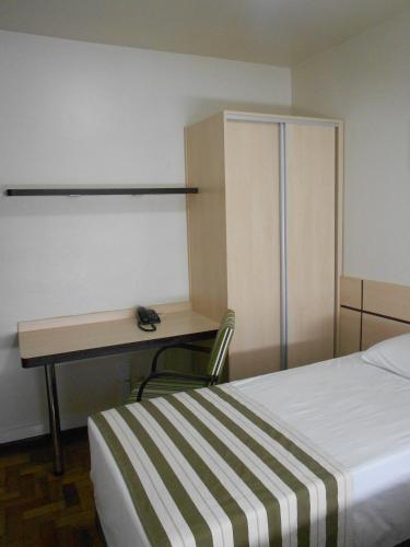 a room with a desk and a bed and a desk and a chair at Colossi Hotel in Porto Alegre