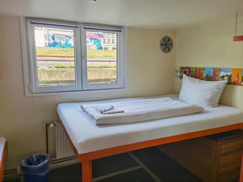 Bett in einem Zimmer mit 2 Fenstern in der Unterkunft Shipotel-Berlin GmbH, Shipotel Eastern & Shipotel Western in Berlin