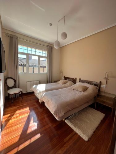 2 Betten in einem Schlafzimmer mit Holzböden und einem Fenster in der Unterkunft Haizea in Bakio