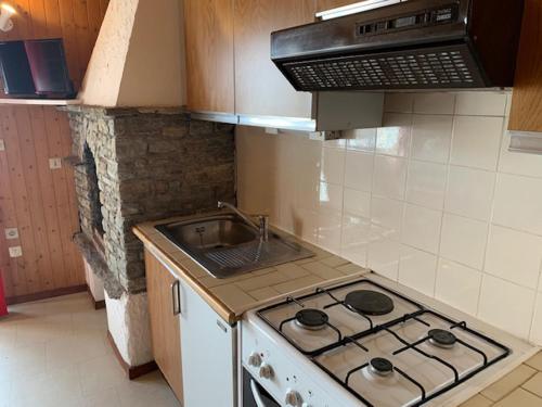 une cuisine avec une cuisinière et un évier dans l'établissement Le p'tit coin montagne, à Bonneval-sur-Arc
