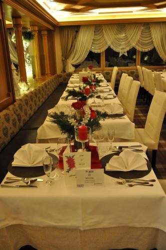 a long dining room with white tables and chairs at Hotel Meida in Pozza di Fassa