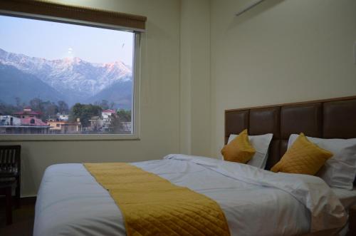 a bedroom with a bed with a large window at HIMALAYA INN in Pālampur