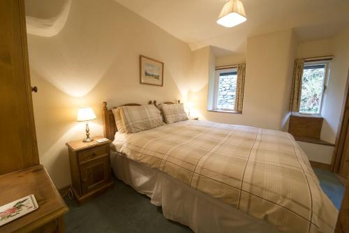 a bedroom with a large bed and a night stand at Rose Bank Cottage Coniston in Coniston