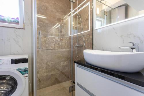 a bathroom with a sink and a washing machine at Apartman Naomi in Krk