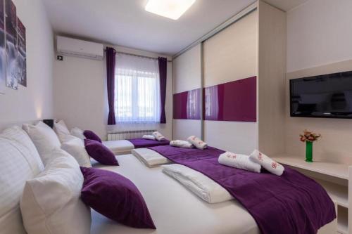 a row of beds in a room with purple pillows at Apartman Naomi in Krk