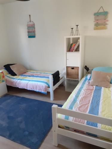 a bedroom with two beds and a blue rug at Coquet appartement 6 personnes avec jardin in Wintzenheim
