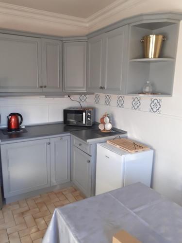 une cuisine avec des armoires blanches et un micro-ondes dans l'établissement Coquet appartement 6 personnes avec jardin, à Wintzenheim