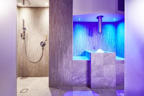 a bathroom with a shower with purple and blue at der grüne Baum Mountain Boutique Hotel in Ehrwald