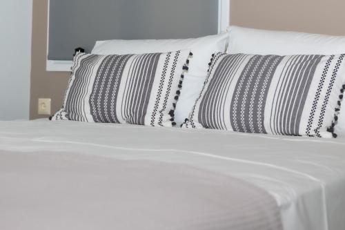a white bed with black and white pillows on it at P&K LUXURY APARTMENTS 1 in Kalamata