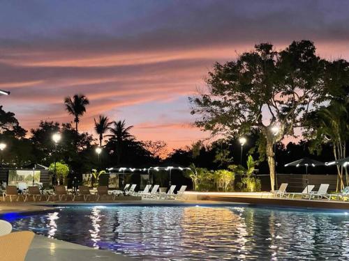 einen Pool mit Stühlen und Sonnenuntergang in der Unterkunft Acogedor departamento en Playa Dorada in San Felipe de Puerto Plata