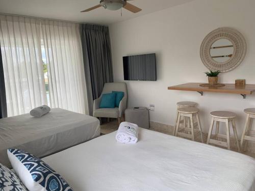 ein Hotelzimmer mit 2 Betten und einem Stuhl in der Unterkunft Acogedor departamento en Playa Dorada in San Felipe de Puerto Plata