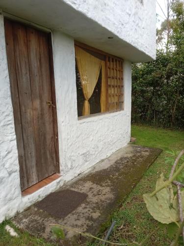 uma pequena casa branca com uma porta e uma janela em ECOHUERTO em Ibarra