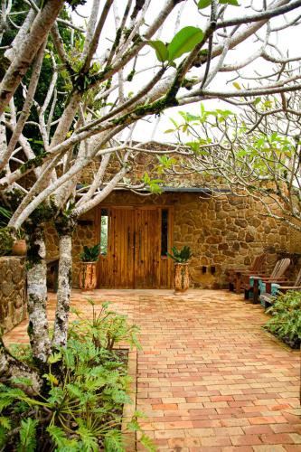 a stone house with a brick patio and a building at TW Guaimbê Exclusive Suítes in Ilhabela
