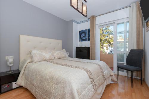 Un dormitorio con una cama y una ventana y una silla. en Casa Buda, en Torrequebrada