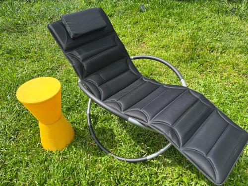 a black chair and a yellow cup on the grass at Container-Spa quente, projetor cine, lareira, churrasqueira-20km de Brotas in Torrinha