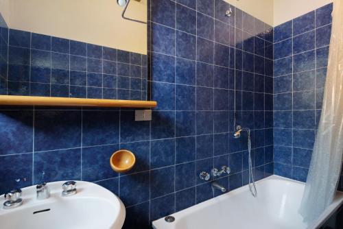 La salle de bains est pourvue de carrelage bleu, d'un lavabo et d'une baignoire. dans l'établissement Bilocale il Castello con parcheggio, à Bonassola