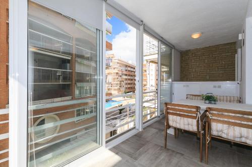 balcón con mesa, banco y ventanas grandes en UHC Alexis Family Apartments, en Salou