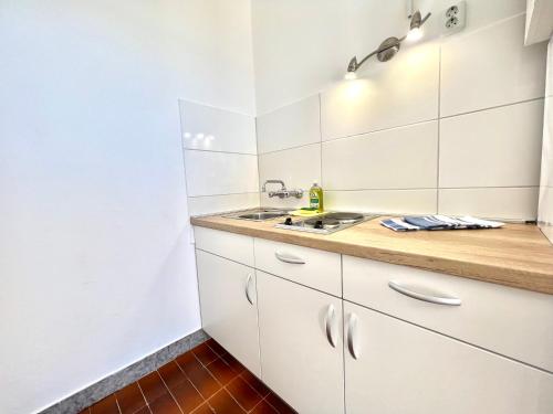 a kitchen with white cabinets and a sink at Apartments Kate in Dramalj
