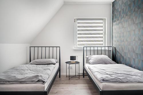 two beds in a room with a window and a table at Noclegi Krańcowa in Zgorzelec