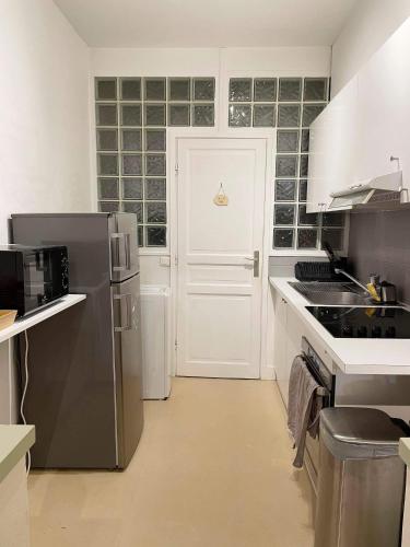 eine Küche mit Küchengeräten aus Edelstahl und einer weißen Tür in der Unterkunft Cosy appartement hyper centre in Saint-Germain-en-Laye