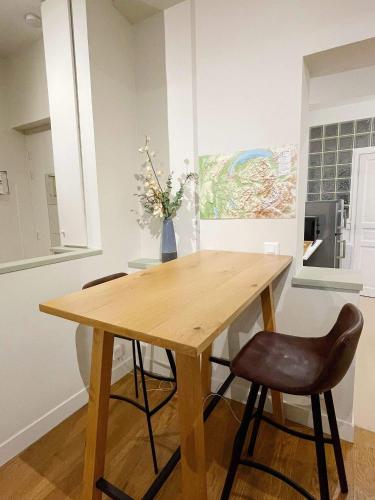 a wooden table with two chairs and a vase with flowers at Cosy appartement hyper centre in Saint-Germain-en-Laye