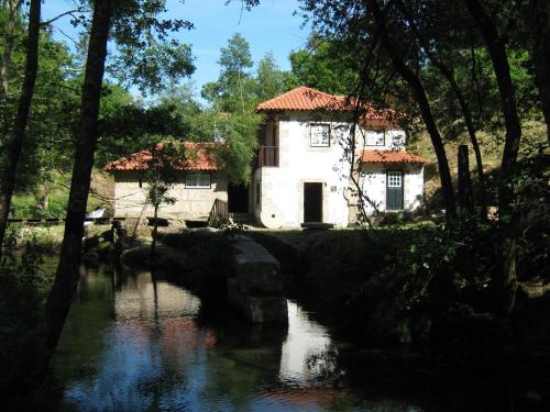 a building next to a river with trees at Moinho da Cruz in Ponte de Lima