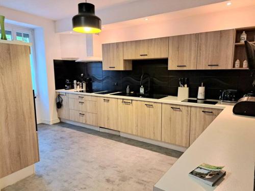 une grande cuisine avec des placards en bois et un mur noir dans l'établissement La Buissonnière Maison Authentique Au Cœur du Village, à Cadouin