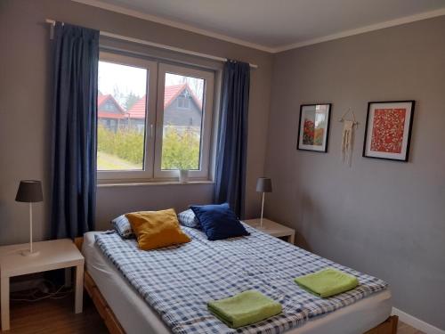 a bedroom with a bed with two pillows and a window at Dom Mazurska Apartamenty in Rydzewo