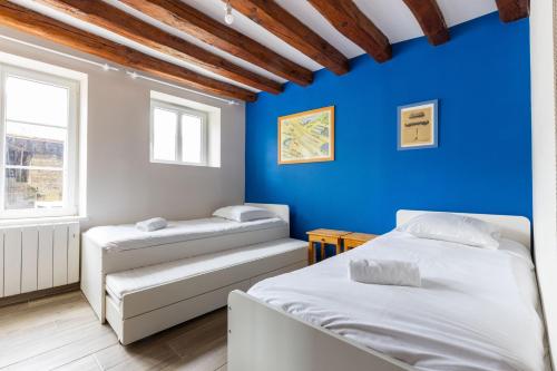 a room with two beds and a blue wall at Le Pressoir in Meusnes
