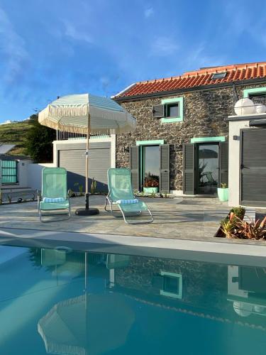 two chairs and an umbrella next to a swimming pool at The Hideaway Madeira in Prazeres