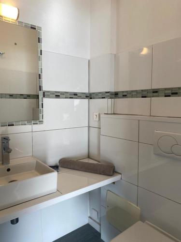 une salle de bain blanche avec un lavabo et un miroir dans l'établissement ALICIA, à Zonza