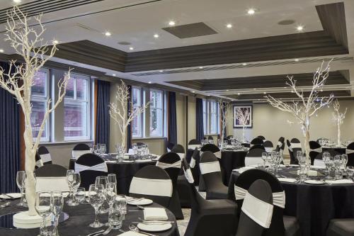 a banquet room with tables and chairs with black and white chairs at Leeds Marriott Hotel in Leeds