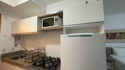 a small kitchen with a microwave and a stove at Refúgio Beira Lago- Life Resort in Brasília