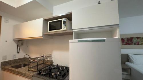 a small kitchen with a microwave and a stove at Refúgio Beira Lago- Life Resort in Brasilia